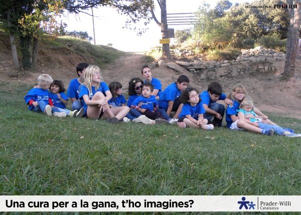  Peu de foto, logo de l’Associació Catalana de Prader Willi. Fotografia d’un grup de joves sentats en un espai a l’aire lliure.