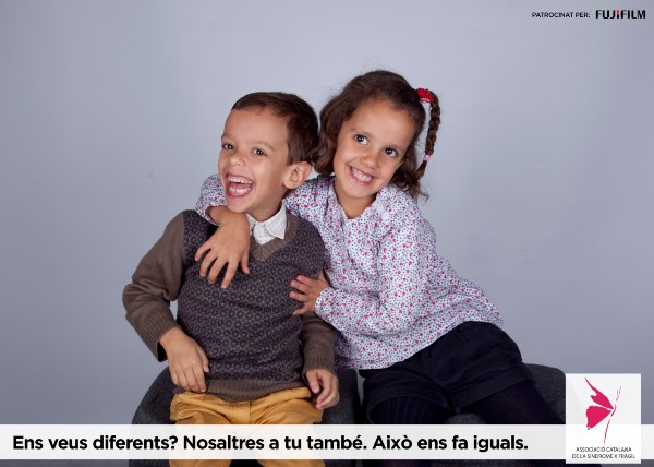 Peu de foto, logo de l’Associació Catalana de la Síndrome X fràgil. Fotografia d’un nen amb un gran somriure i una nena somrient i abraçant al nen.